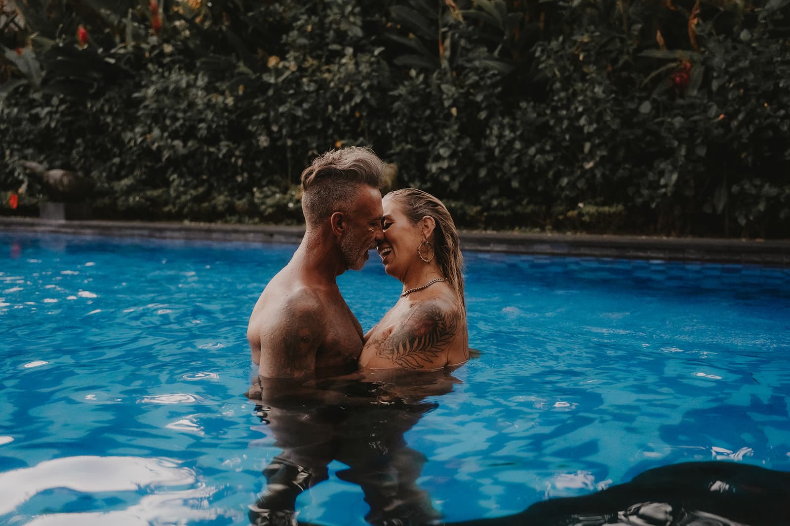 Rex and Rebelle forehead to forehead, laughing together in the water